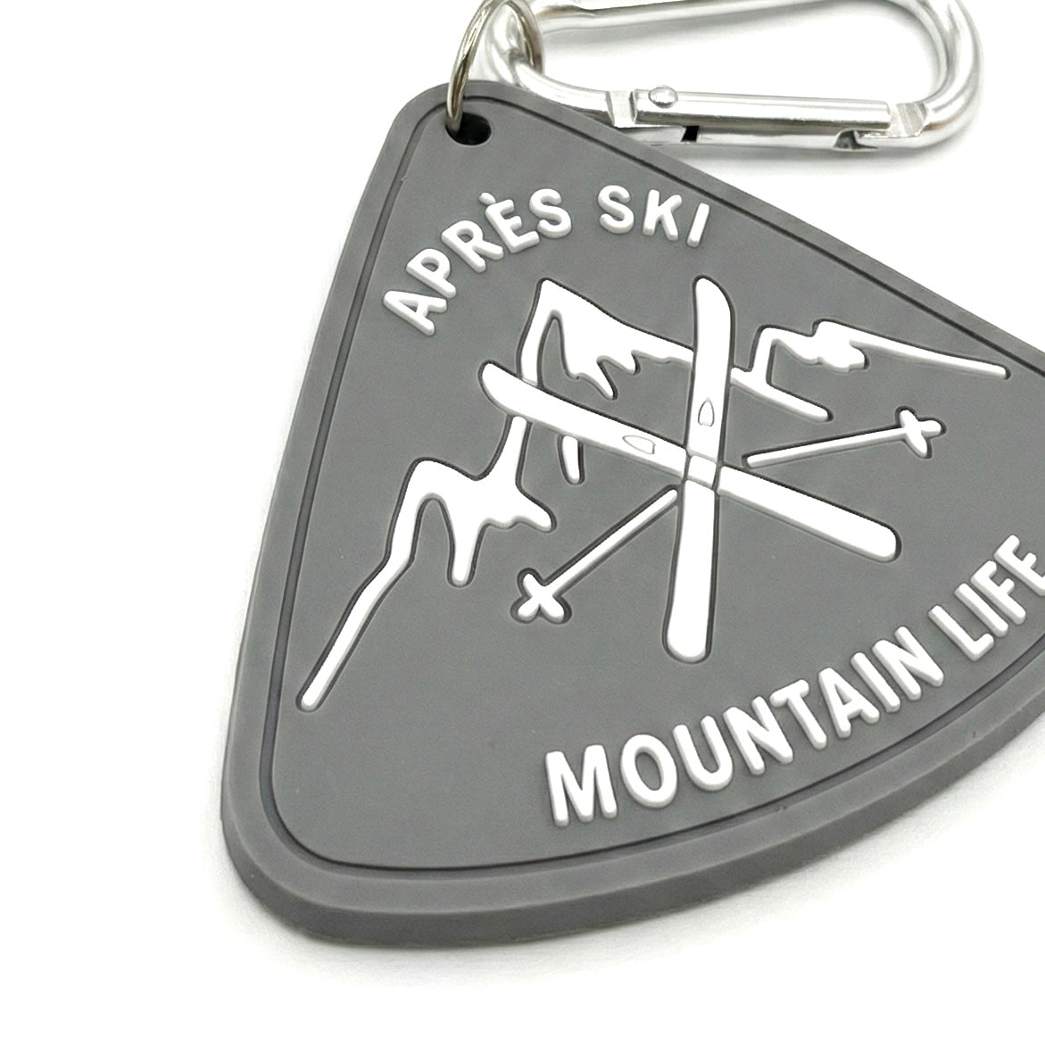 Close up of rubber bag charm details. High-quality 3D raised lettering with silver carabiner clip. Durable ski souvenir and keychain.