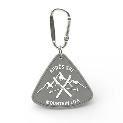 Sunday Said Après Ski bag charm. Grey triangular rubber keychain featuring crossed skis and Mountain Life text. Perfect winter sport gift for skiers.