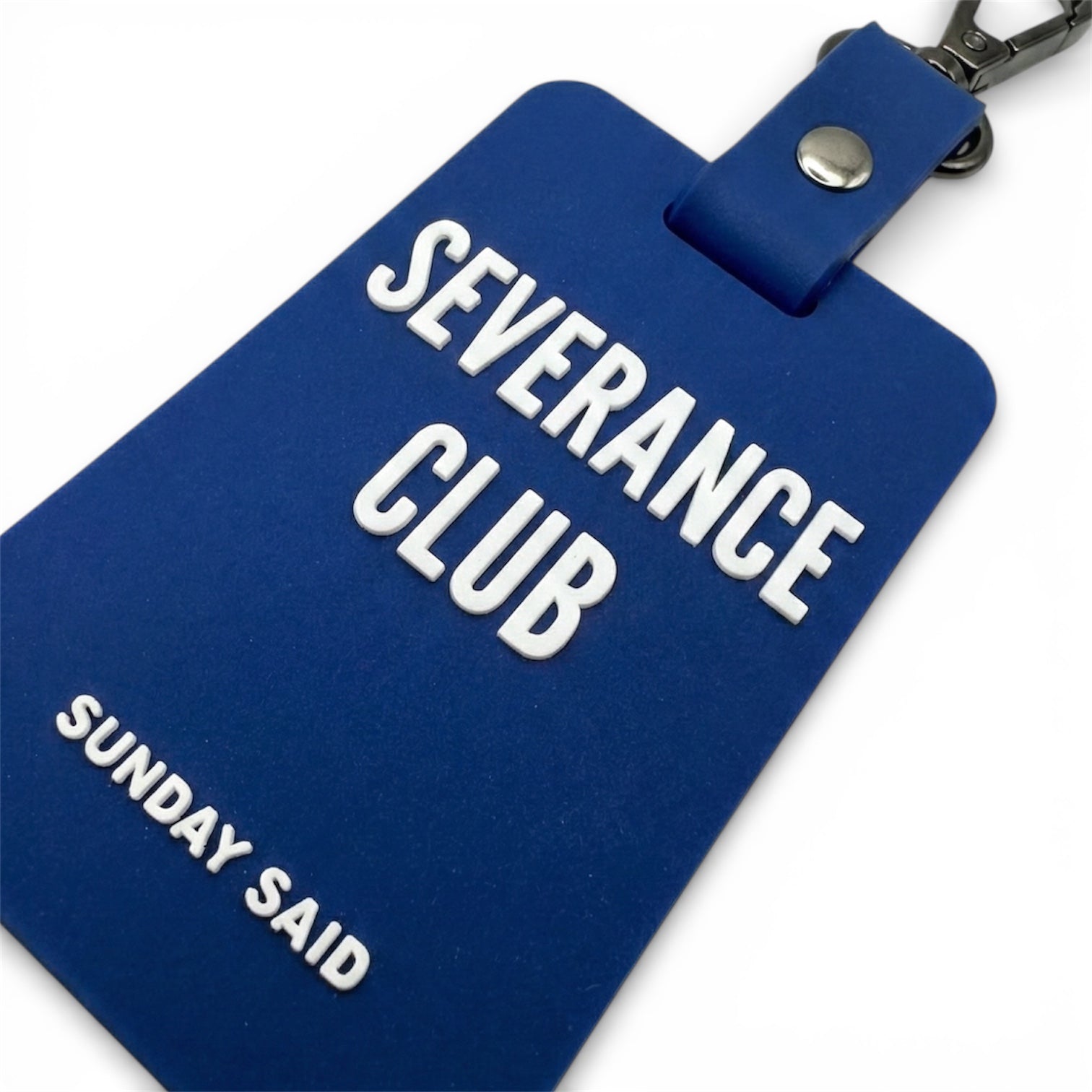 Close up of 3D raised white lettering on blue rubber charm. High quality silicone texture detail showing Severance Club text. Durable bag accessory.