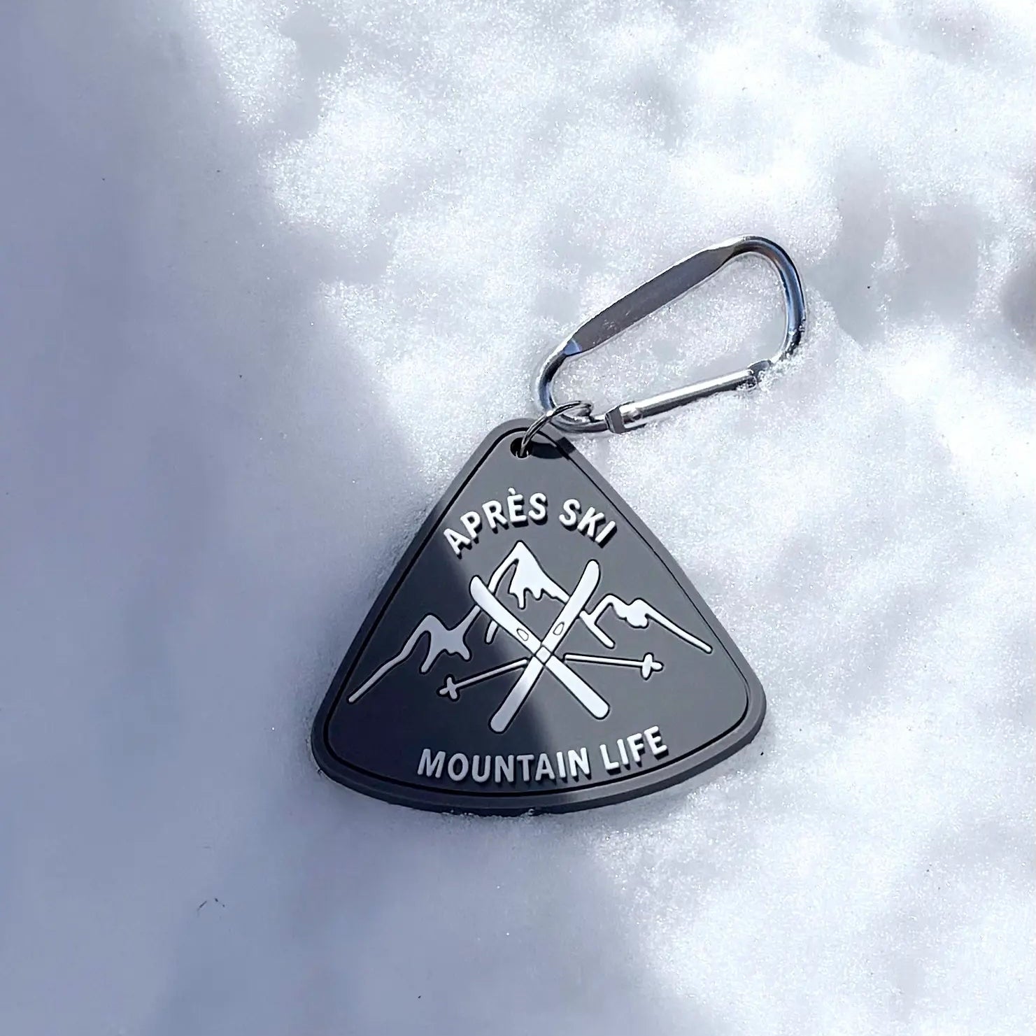 Triangular keychain with 'Apres Ski Mountain Life' text on a snowy background