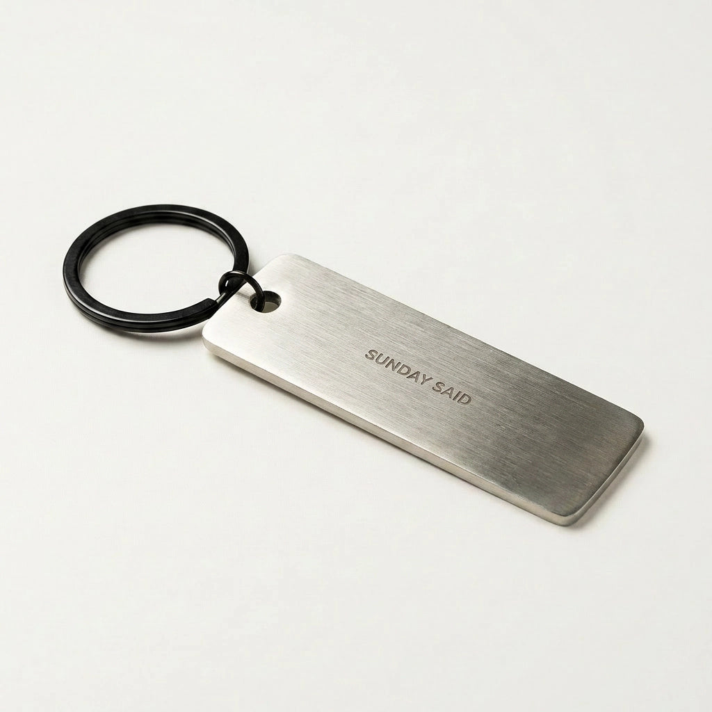 Metal keychain with 'SUNDAY SAID' engraving on a white background
