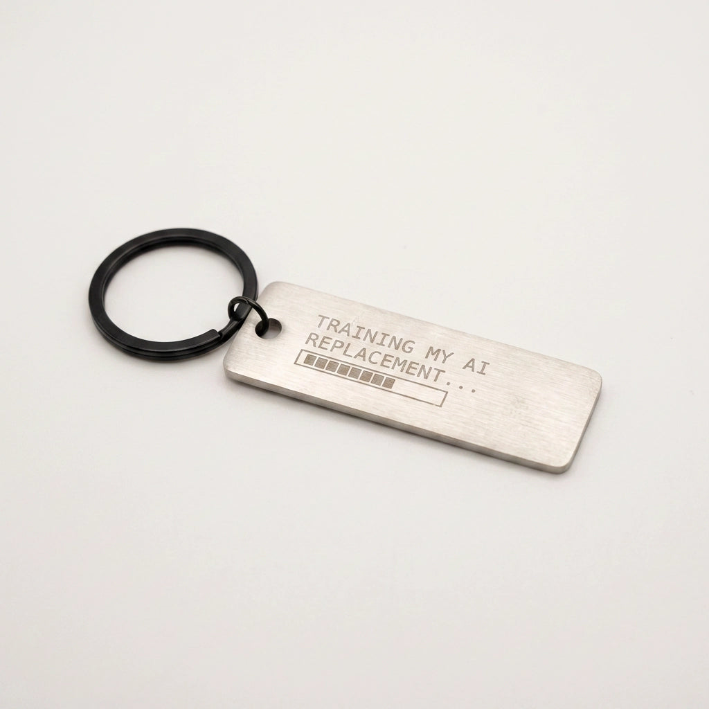Metal keychain with text 'Training my AI replacement...' on a light gray background
